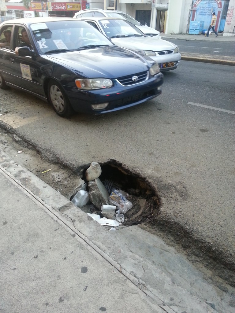Este hoyo está localizado en el tramo de la avenida Las Carreras, casi esquina avenida Juan Pablo Duarte, en sentido hacia el Monumento a los Héroes de la Restauración.