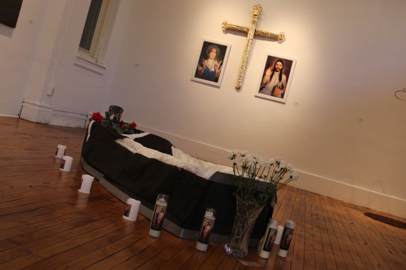 Carlos Manuel Rivera expone su obra “El a muelto”, 2016. Instalación-Poema-Performance, en colaboración con Elsie Deliz y Luis Carle. En el fondo: Melanie González muestra las obras “Ghetto Mary”, 2015. “Papi Jesus”, 2015. “Doorknocker Altar Cross”, 2015.